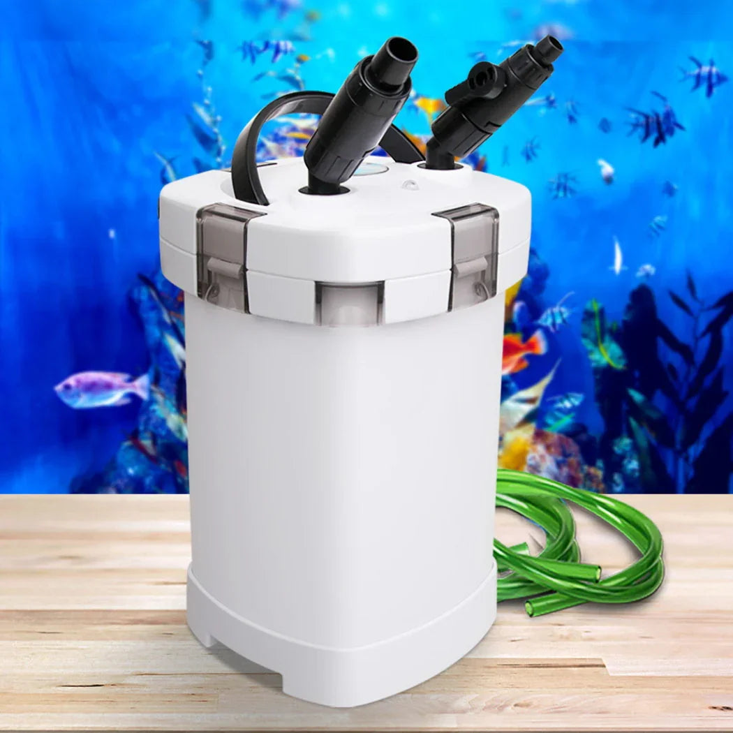 Aquarium canister filter with green hose on table, fish tank in background