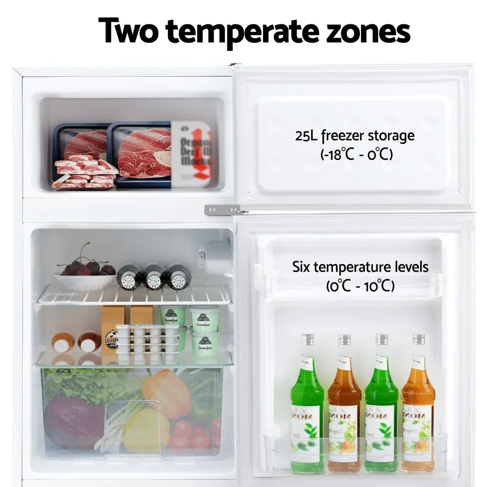 Compact fridge freezer with two temperature zones, showing organized food and drinks storage.