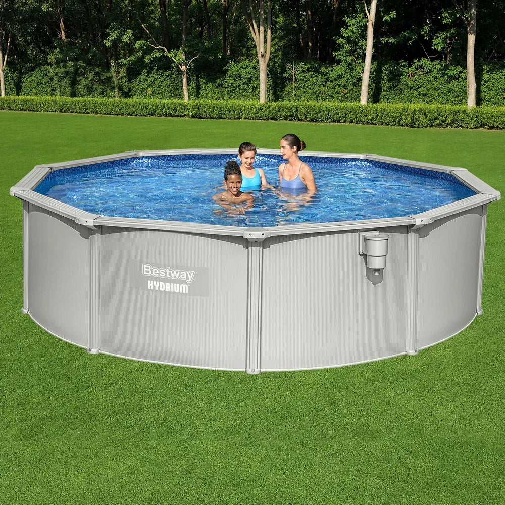 Above ground round pool with three people in clear water on green grass outdoors