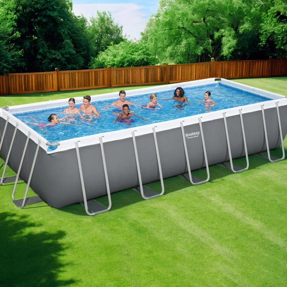 Large rectangular above ground pool with people swimming in a backyard setting