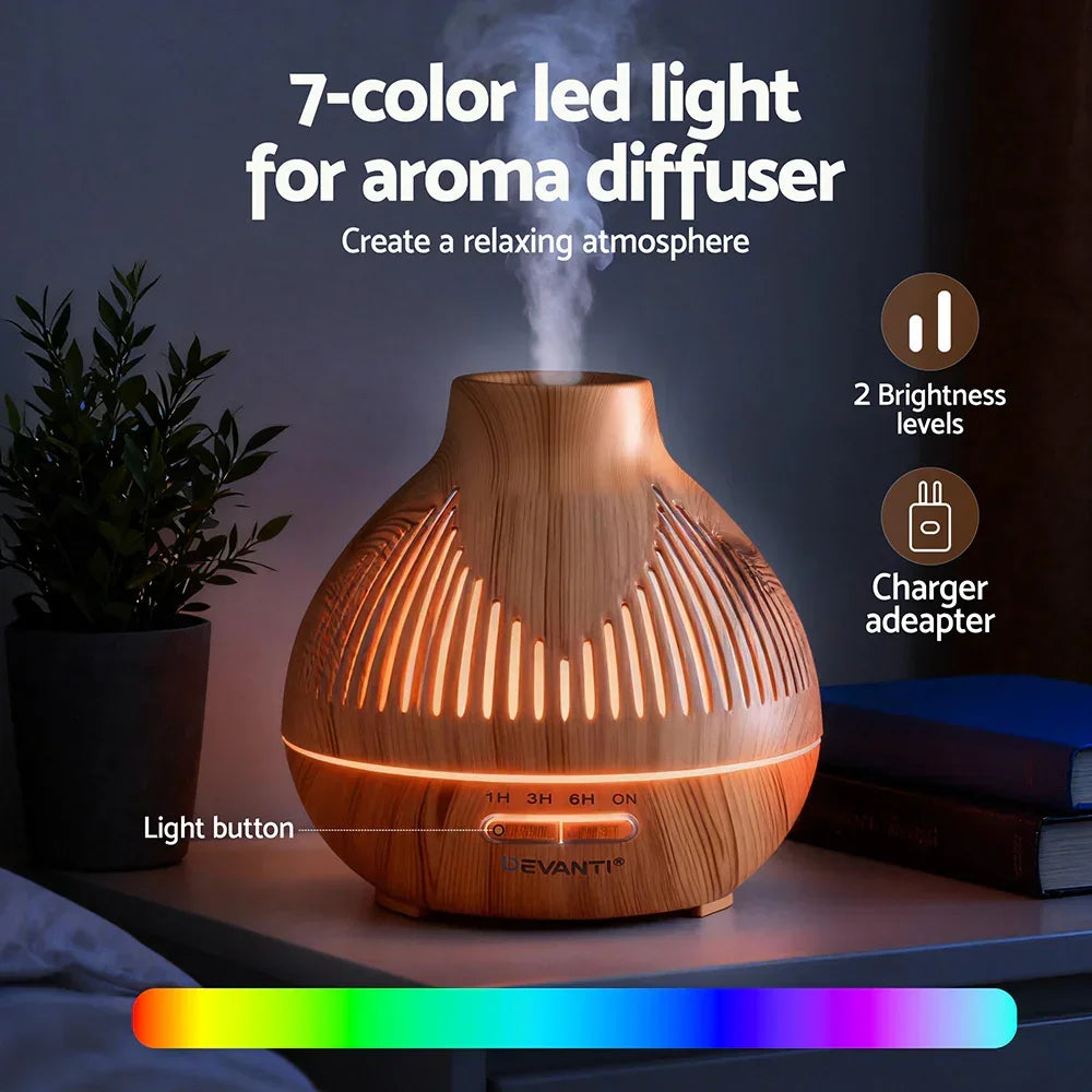 7-color LED aroma diffuser with wood grain finish, emitting mist and ambient light on a bedside table