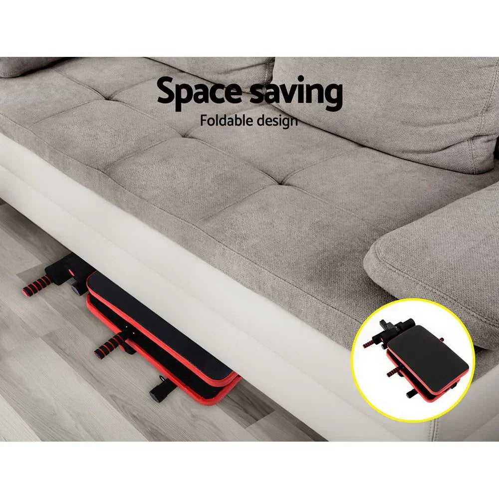 Foldable sit-up bench stored under sofa, space-saving home gym equipment.