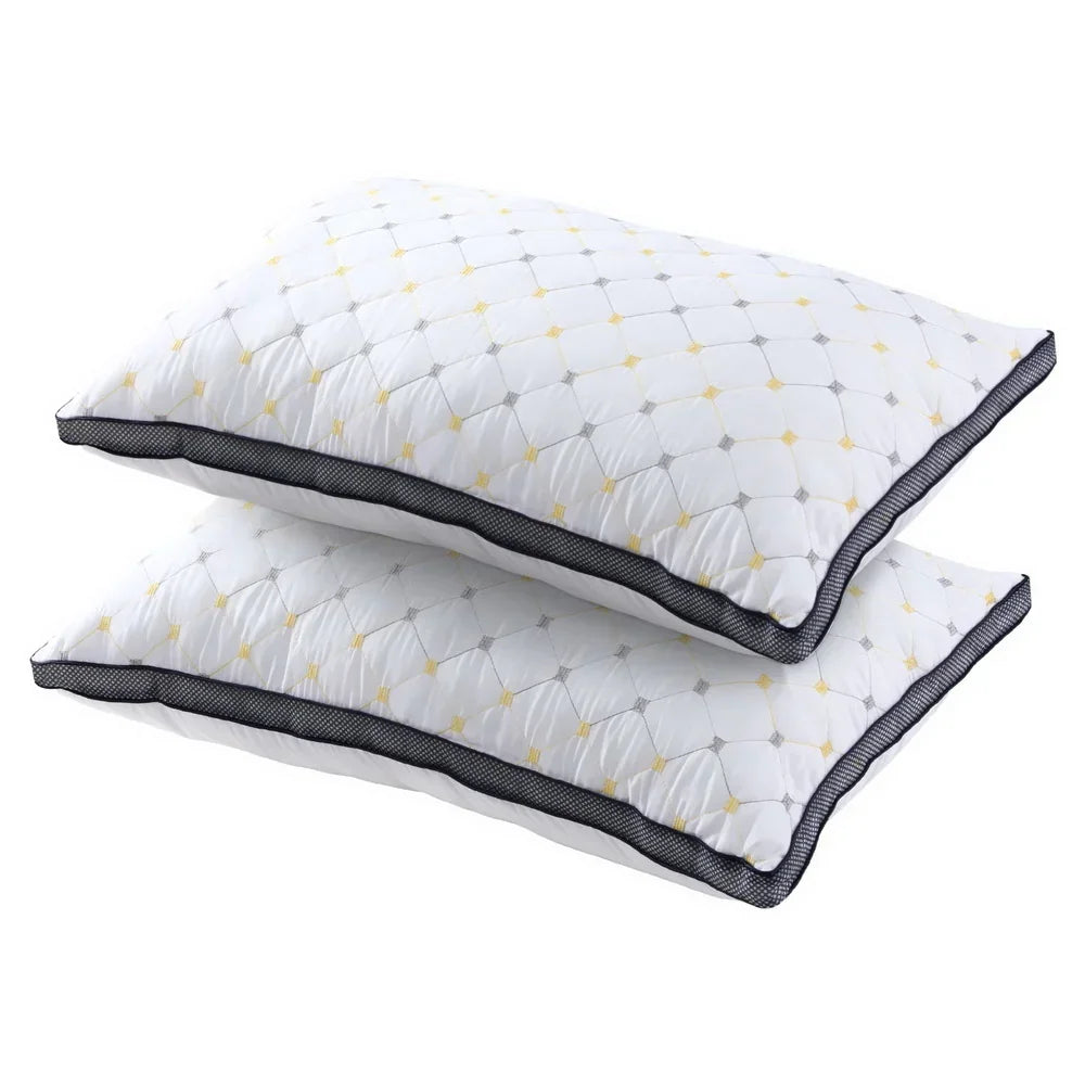 Pair of white quilted pillows with yellow and gray diamond stitching and black trim