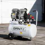 Portable air compressor with gauges and wheels on concrete surface outdoors
