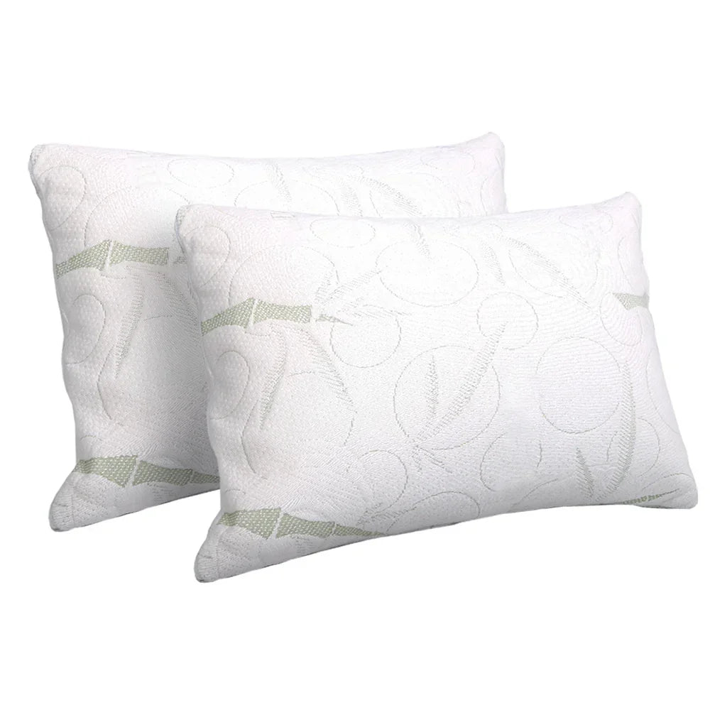 Pair of white, patterned bed pillows with subtle green accents on a plain background