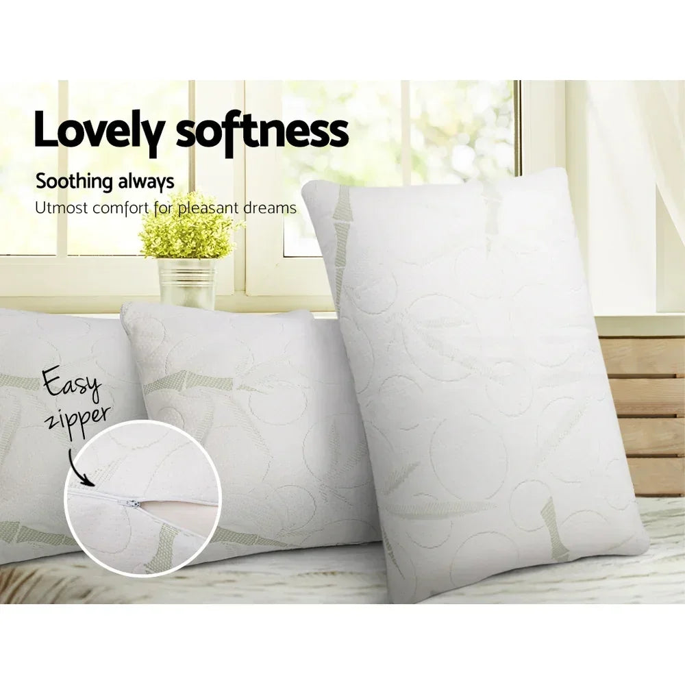 Two soft white pillows with decorative stitching and easy zipper, displayed on a bed by a window.