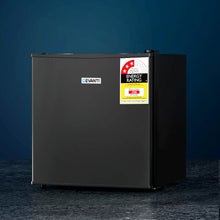 Black compact bar fridge with energy rating sticker on dark background