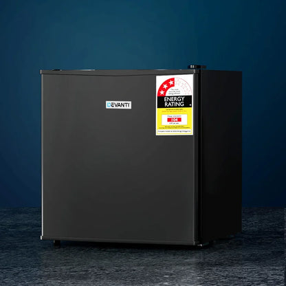 Black compact bar fridge with energy rating sticker on dark background
