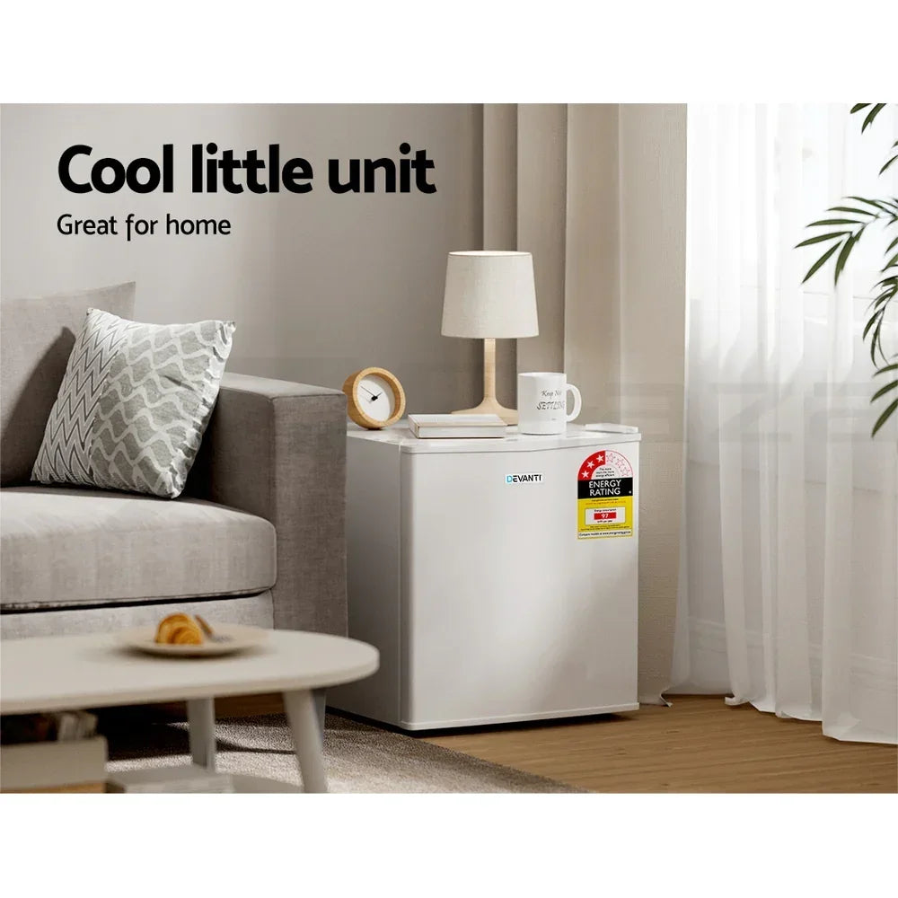White compact mini fridge next to a sofa in a modern living room with lamp and decor on top.