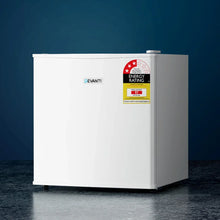 White compact bar fridge with energy rating label, set against a blue background