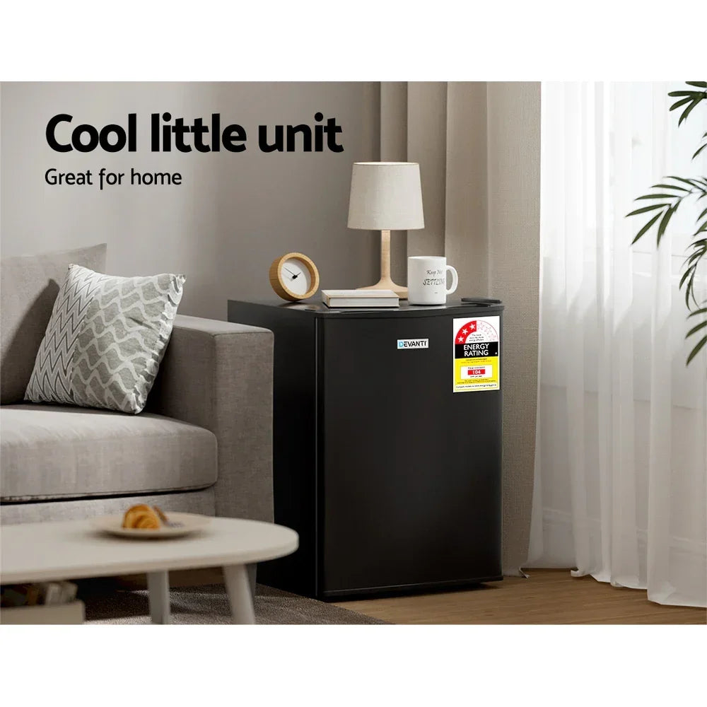 Black mini fridge in modern living room beside sofa, styled with lamp, mug, and clock.
