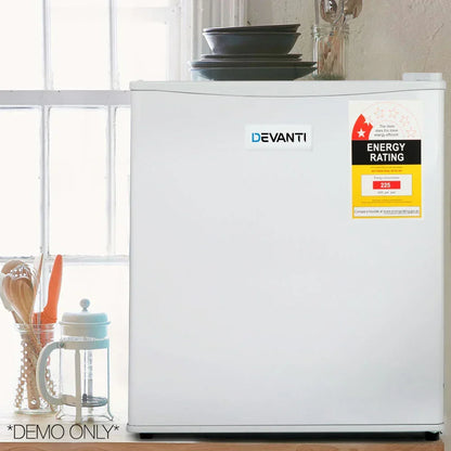 Compact white mini fridge with energy rating sticker in a kitchen setting, utensils beside.