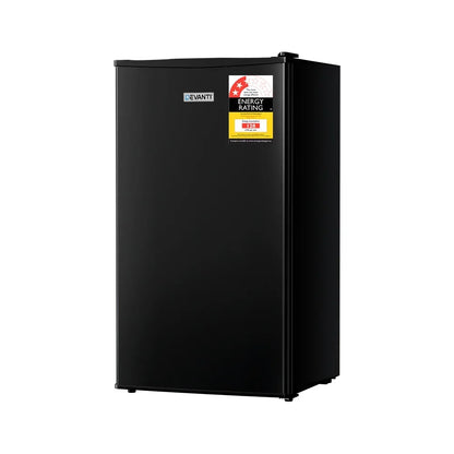 Black mini fridge with energy rating sticker on door, freestanding compact refrigerator.