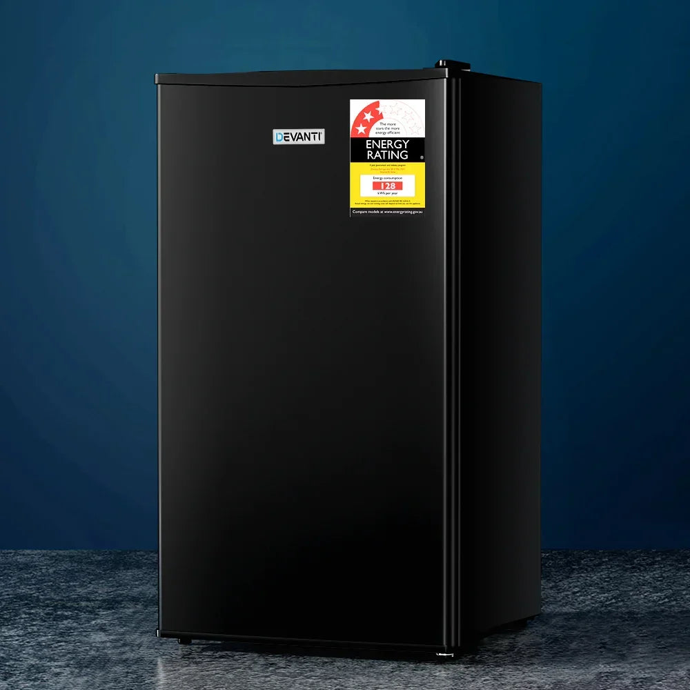 Black single-door mini fridge with energy rating label on blue background