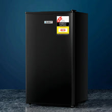 Black single-door mini fridge with energy rating label on blue background