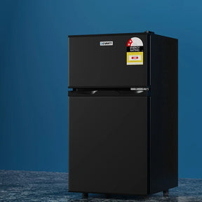 Black two-door compact refrigerator with freezer, energy rating label, on blue background