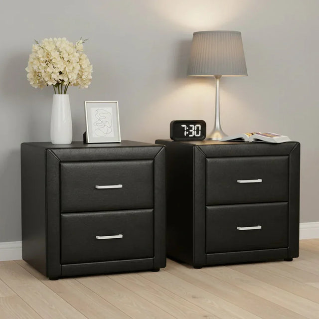 Pair of modern black bedside tables with two drawers, lamp, clock, flowers, and decor