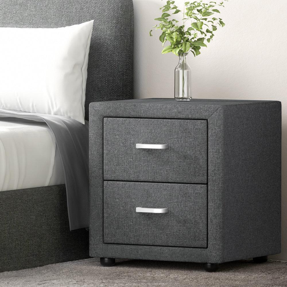 Modern grey fabric bedside table with two drawers, silver handles, and a glass vase