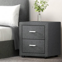 Modern grey fabric bedside table with two drawers, silver handles, and a glass vase