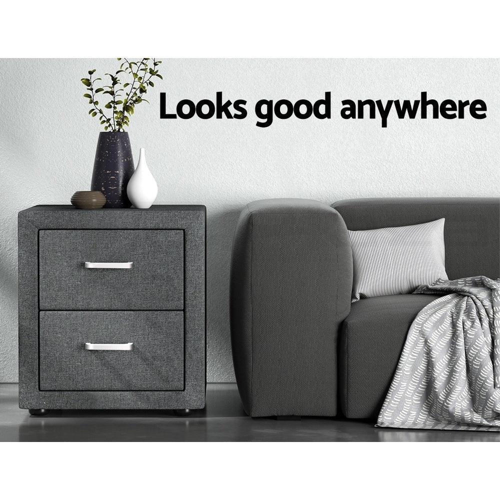 Modern grey fabric bedside table with two drawers next to a grey sofa and vases, home decor