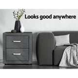 Modern grey fabric bedside table with two drawers next to a grey sofa and vases, home decor