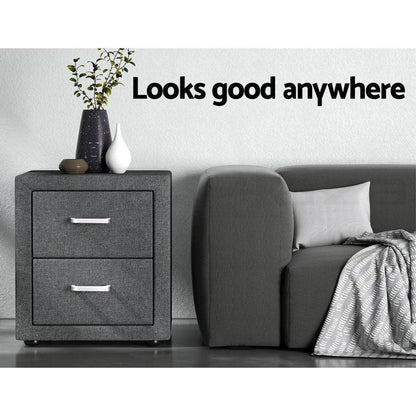 Modern grey fabric bedside table with two drawers next to a grey sofa and vases, home decor