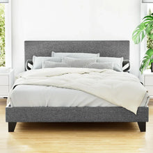 Modern grey upholstered bed frame with headboard, neatly made in a bright bedroom