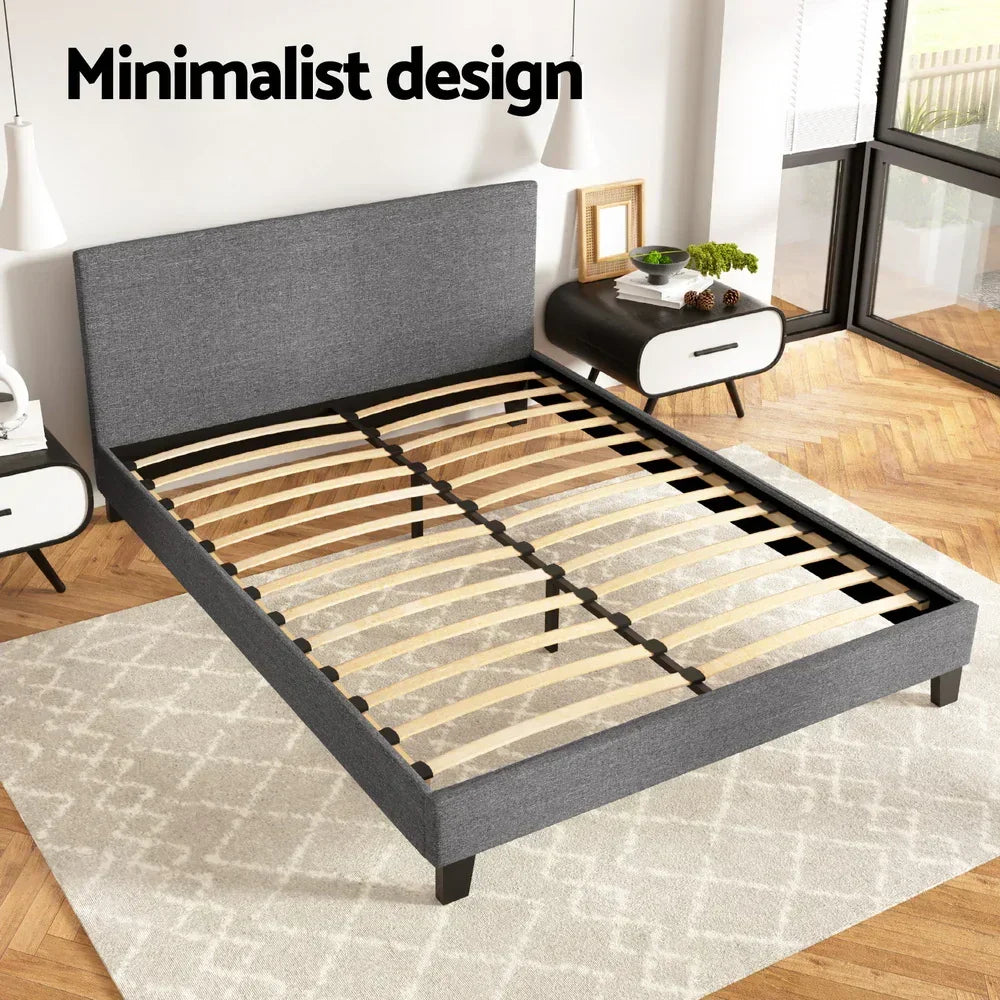 Modern grey upholstered bed frame with wooden slats in a minimalist bedroom