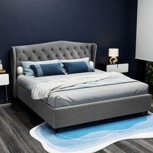 Grey upholstered bed frame with tufted headboard, blue bedding and pillows, modern bedroom setting