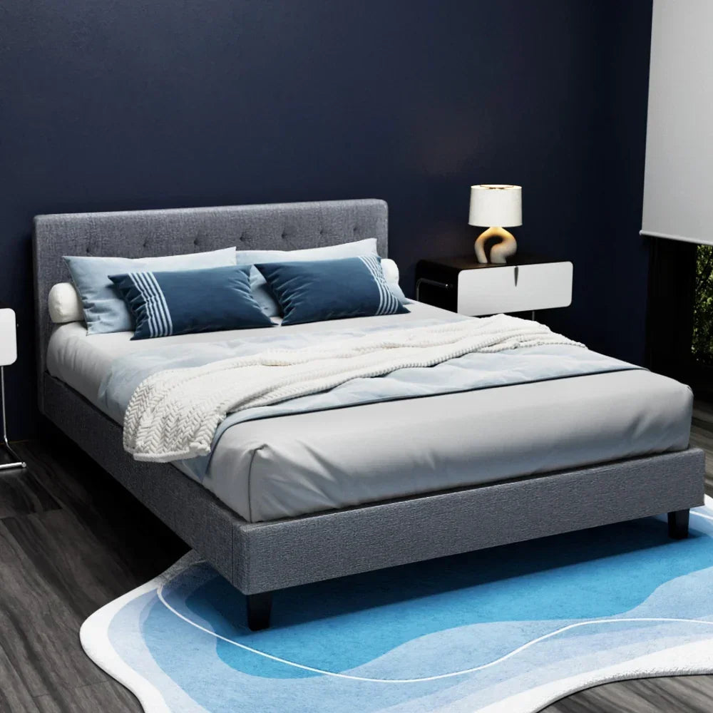 Modern grey upholstered bed frame with blue bedding in contemporary bedroom