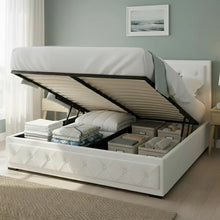 White upholstered storage bed with lift-up mattress, organized bedding and boxes inside