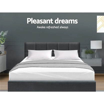 Modern bedroom with grey upholstered bed frame, white bedding, pillows, and bedside tables