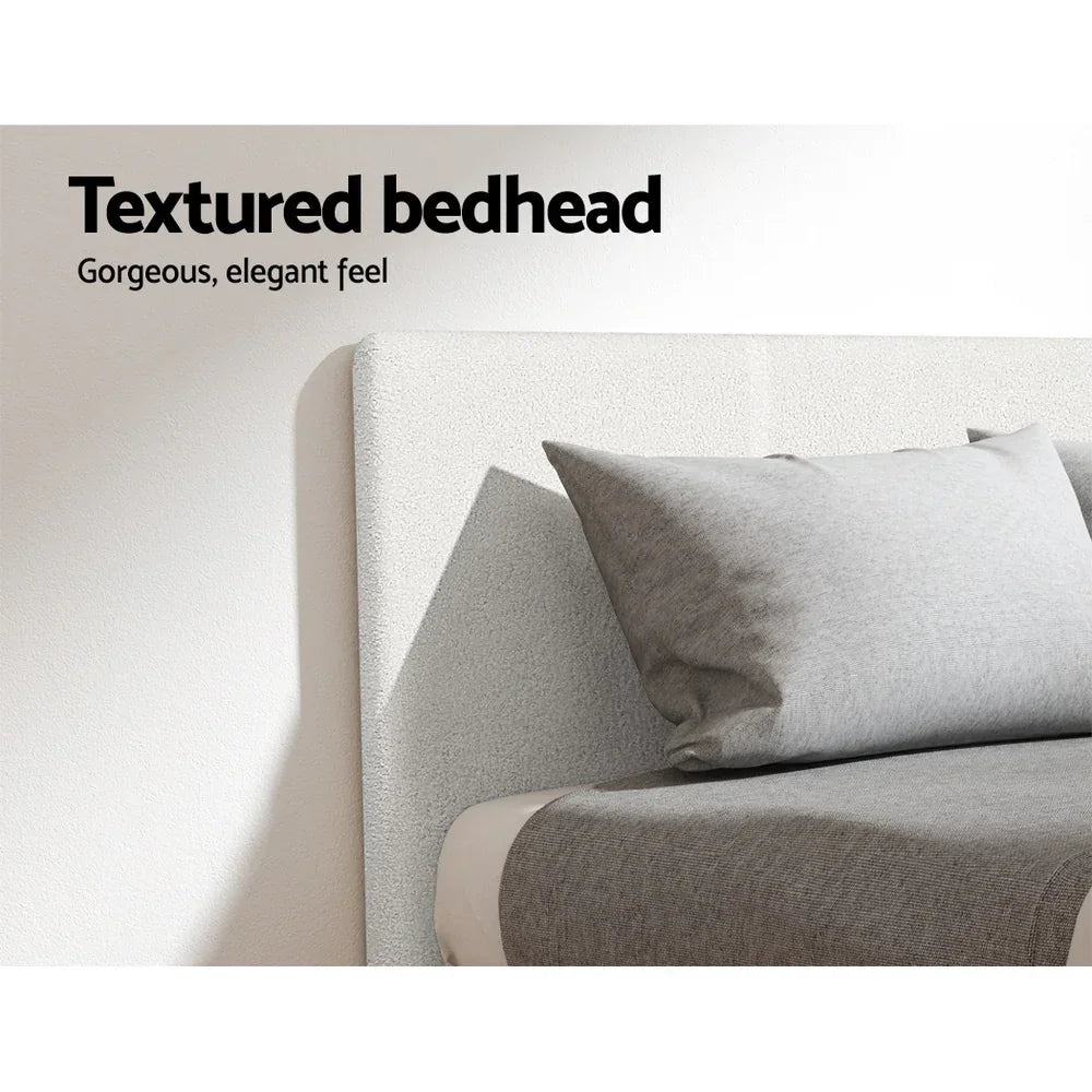 Textured bedhead with soft grey pillow and blanket, bedroom furniture detail.