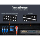 Black pegboard wall with slots for bins, pin holes for tool holders, and organized tools.