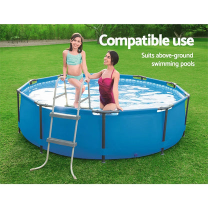 Two people using a metal ladder to enter a round blue above-ground swimming pool on grass