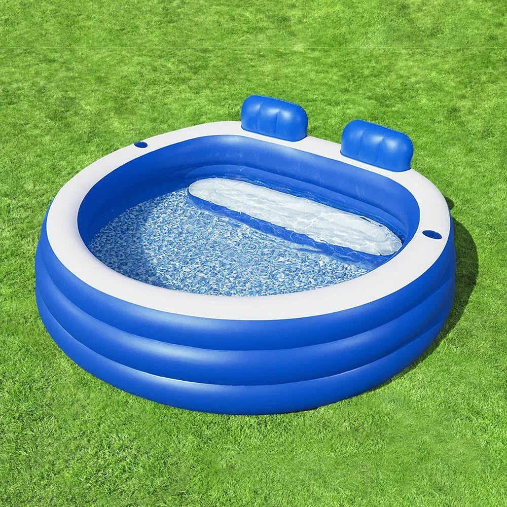Blue inflatable kiddie pool with headrests on green grass, outdoor summer setting.