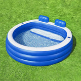 Blue inflatable kiddie pool with headrests on green grass, outdoor summer setting.