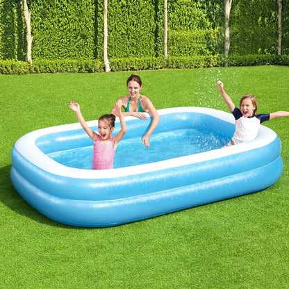 Children playing in a blue inflatable rectangular pool on green grass outdoors