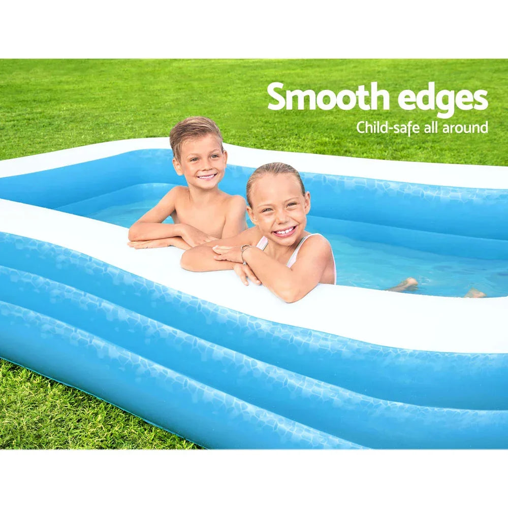 Two smiling kids in a blue inflatable pool with smooth white edges on green grass outdoors