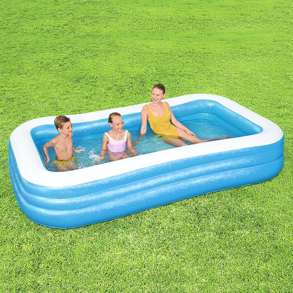 Rectangular inflatable pool with two children and an adult relaxing outdoors on grass