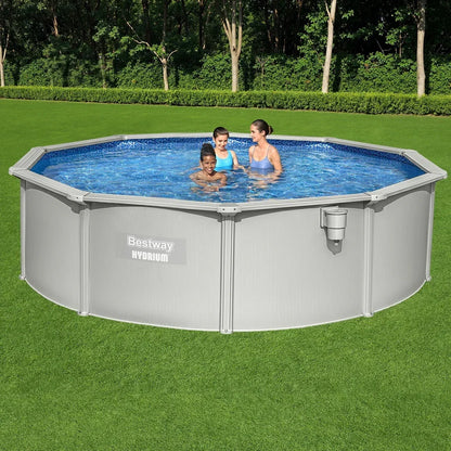 Above ground round pool with three people in clear water on green grass outdoors