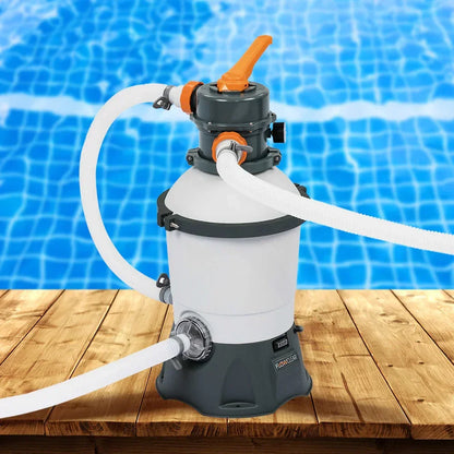 Sand filter pump for swimming pool with hoses on wooden deck by blue pool water