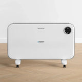 White electric panel heater with control panel and wheels on wooden floor indoors
