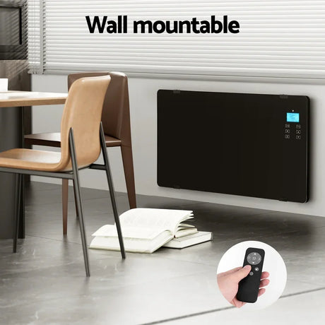 Wall mounted black glass panel heater with digital display and remote control in modern room.
