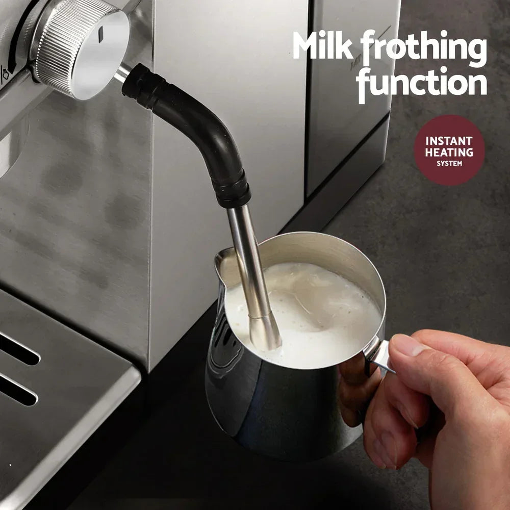 Espresso machine steam wand frothing milk in a stainless pitcher for coffee drinks