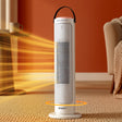 White tower heater with oscillation feature shown in a cozy living room setting, blowing warm air