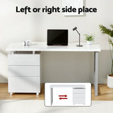 Modern white office desk with drawers, laptop, lamp, and plants, reversible drawer setup