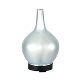 Modern glass essential oil diffuser with iridescent finish and black base on white background