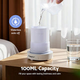 White essential oil diffuser with 100ml capacity on bedside table, water being poured in