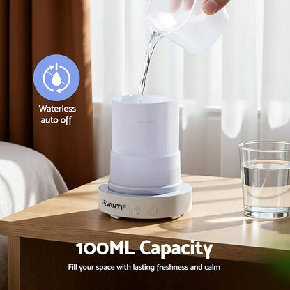 White essential oil diffuser with 100ml capacity on bedside table, water being poured in